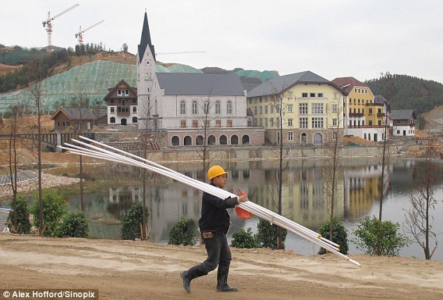 A workman helps recreate the mountain of idyll of Hallstatt, complete with a lake, concert hall and luxury homes