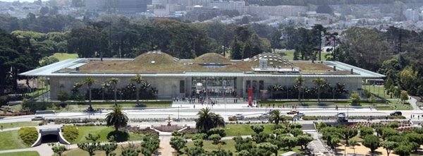 The California Academy of Sciences, Golden Gate Park, San Francisco, California, as viewed from the tower of the de Young Museum (with the University of California, San Francisco Parnassus campus at the base of Mount Sutro in the distance). The building has a green roof. The three largest "hills" on the roof overlie the planetarium, swamp exhibit and rainforest exhibit (left to right). Photo credit: WolfmanSF. Licensed under CC BY-SA 3.0